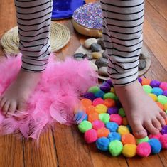 a child's feet with pink and green pom - poms on the floor