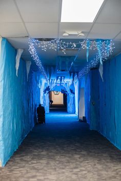 an empty hallway with blue walls and white lights on the ceiling is lit up at night