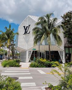 a building with palm trees in front of it and the word louis vu on top