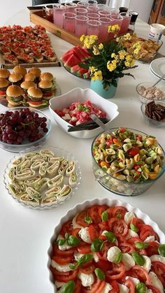 a table topped with lots of food and plates filled with sandwiches, salads and other foods