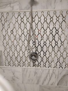 the shower head is attached to the tile wall in this marble tiled bathtub area