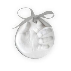 an ornament shaped like a hand holding a baby's hand with a ribbon around it