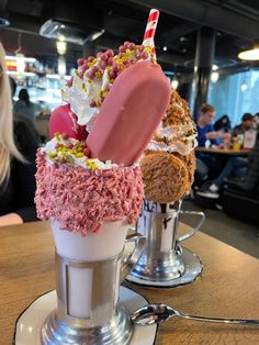 an ice cream sundae with pink and white toppings in a cup on a table