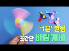 a hand holding a colorful pinwheel on top of a blue background with korean text