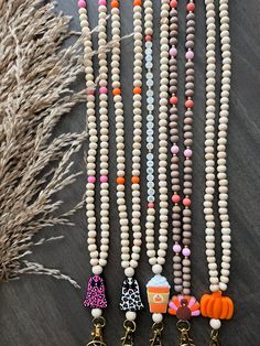 several necklaces are laid out on a table next to some dried grass and an orange pumpkin