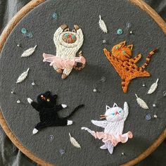 an embroidery project with cats and birds on it's back side, surrounded by feathers