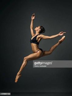 a female ballet dancer in the air with her arms outstretched and legs spread out, posing for