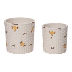 two cups with bees on them sitting next to each other in front of a white background