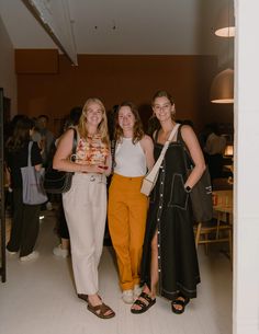 three women standing next to each other in a room