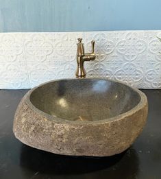 a stone sink sitting on top of a black counter next to a faucet