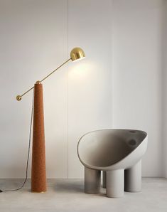 a lamp that is on top of a table next to a bowl shaped chair with a long arm