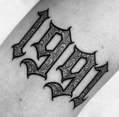 a black and white photo of a tattoo design on the leg with letters in gothic style