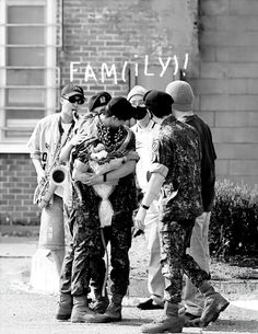 a group of people standing next to each other in front of a building with graffiti on it