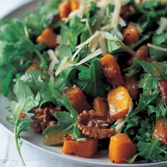 a white plate topped with greens and carrots on top of a bed of cheese