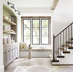 a living room with white walls and wooden floors, stairs leading up to the second floor