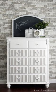 a white dresser sitting in front of a brick wall