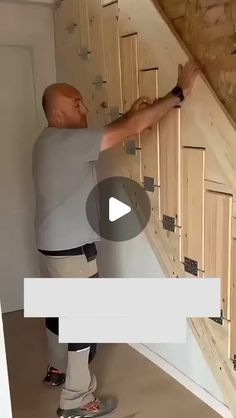 a man standing on top of a wooden stair case next to a wall with drawers