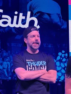 a man with his arms crossed standing in front of a blue background and the words faith on it