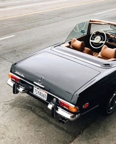 an old black convertible car parked on the side of the road