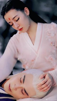 a woman is getting her hair done by another woman in a white dress with flowers on her head