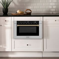 a kitchen with white cabinets and black counter tops has an oven built into the wall