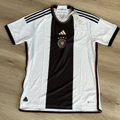 a black and white soccer jersey sitting on top of a wooden floor