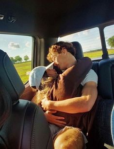 a man and woman sitting in the back seat of a car with their arms around each other