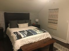 a bed sitting in a bedroom next to a wooden dresser and lamp on top of a hard wood floor