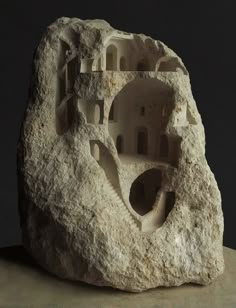 a rock with some kind of building on it's side and another type of structure in the middle