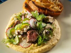 an omelet with meat, vegetables and bread is on a white plate next to a blue napkin