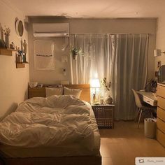 an unmade bed sitting in a bedroom next to a desk with a lamp on it