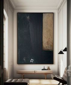 a painting hanging on the wall above a bench in a room with white walls and wooden flooring