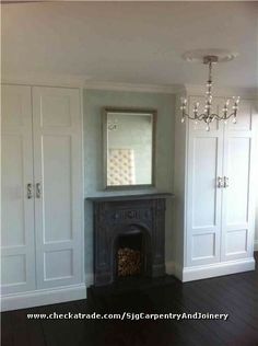 an empty room with a fireplace, mirror and closets on either side of it