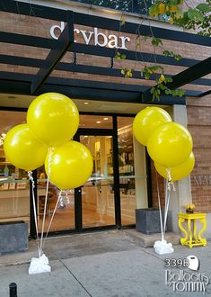 yellow balloons are in front of the entrance to a store that is open for business