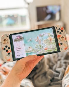 a person holding up a nintendo wii game controller in front of a tv screen with an animal scene on it