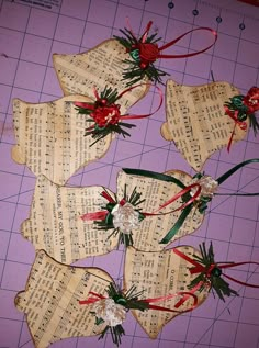 four pieces of paper with flowers and ribbons on top of sheet music sheets that are laid out on a cutting board