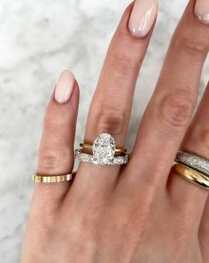 a woman's hand with three different rings on her fingers and one ring in the middle