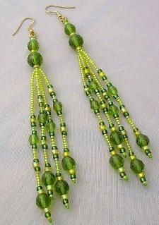 two pairs of green beaded earrings on a white tablecloth with beads hanging from them