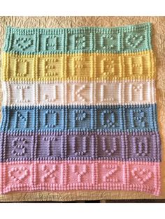 a crocheted blanket with different colors and numbers on it, sitting on top of a bed