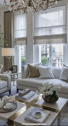 a living room filled with furniture and a chandelier hanging over the top of it