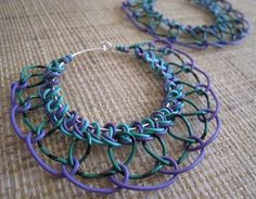 two pieces of blue and green yarn on a table with some silver hoop earrings hanging from it