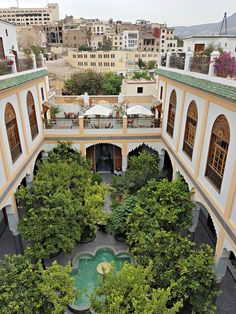 an aerial view of a courtyard with tables and umbrellas in the center, surrounded by trees