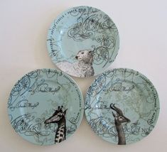 three plates with giraffes on them sitting next to each other in front of a white wall