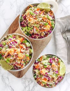 three bowls filled with coleslaw, carrots and celery on top of a wooden cutting board