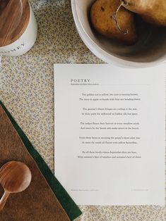 a table topped with wooden spoons next to a bowl of potatoes and a paper