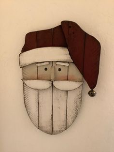 a wooden mask mounted to the side of a wall with a red hat on it