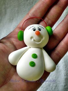 a hand holding a small white and green snowman ornament