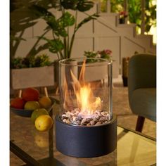 a glass fire pit sitting on top of a table next to some fruit and vegetables