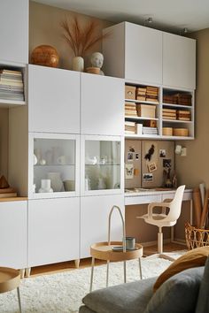 a living room filled with furniture and lots of books on top of white cupboards