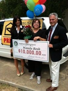 two women and a man holding a check for $ 10, 000 in front of a van